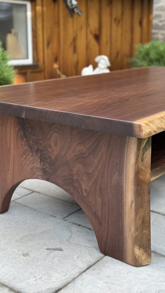 Black walnut coffee table with half-moon wood base and lower shelf