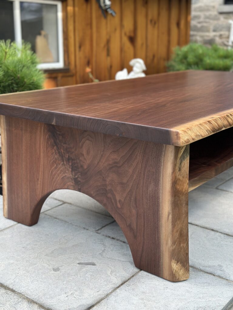 Black walnut coffee table with half-moon wood base and lower shelf